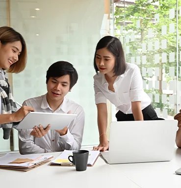 Three professionals in business attire, focused on a laptop screen. ZAcoders Software company that offers the Digital Marketing and development Services in usa.